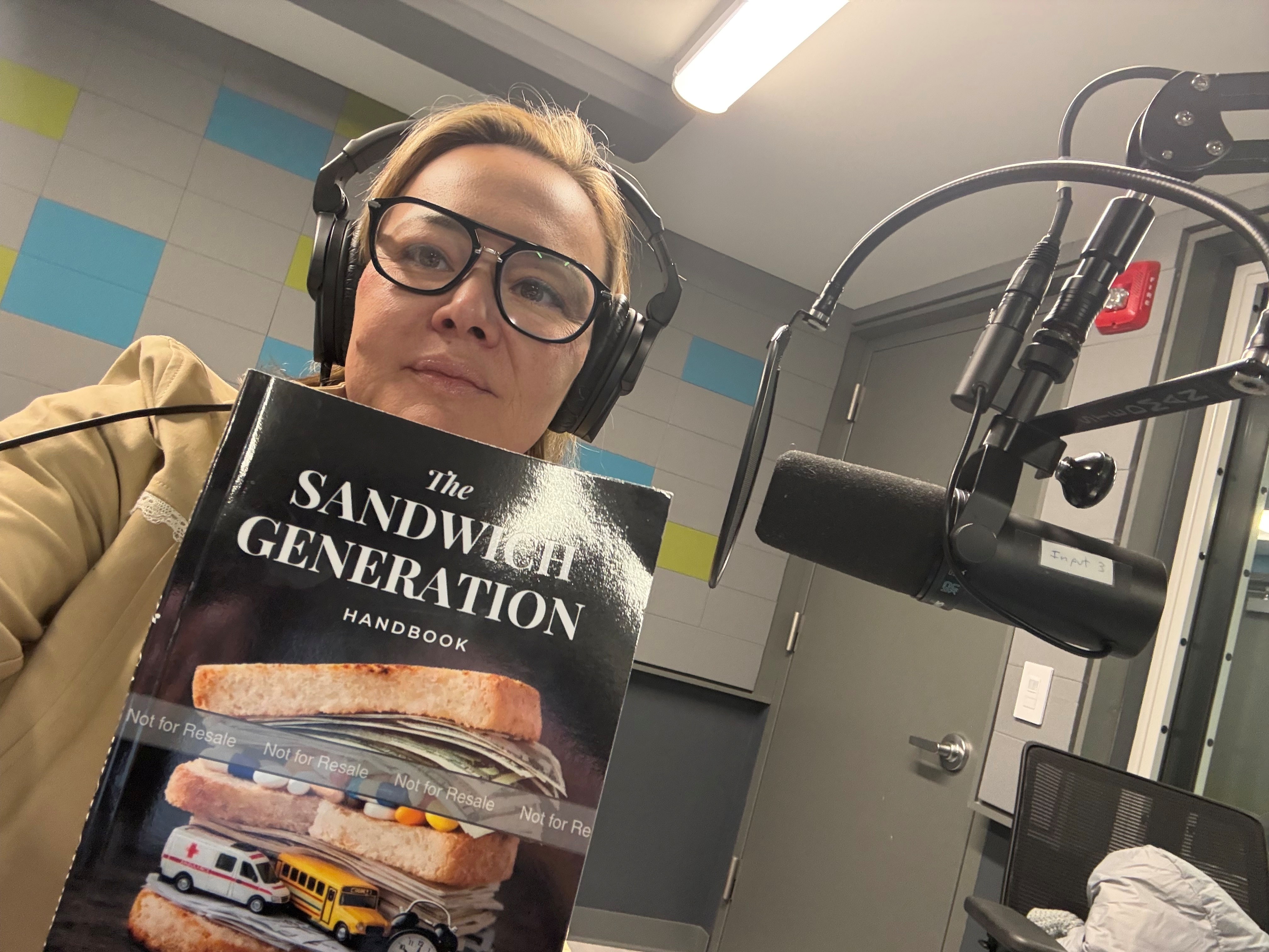 Dr. Irina Koyfman holding The Sandwich Generation Handbook in the recording studio
